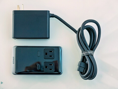 Power adapter with dual USB outlets and coiled cable on white surface.